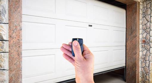 Someone opening a white garage door with a remote